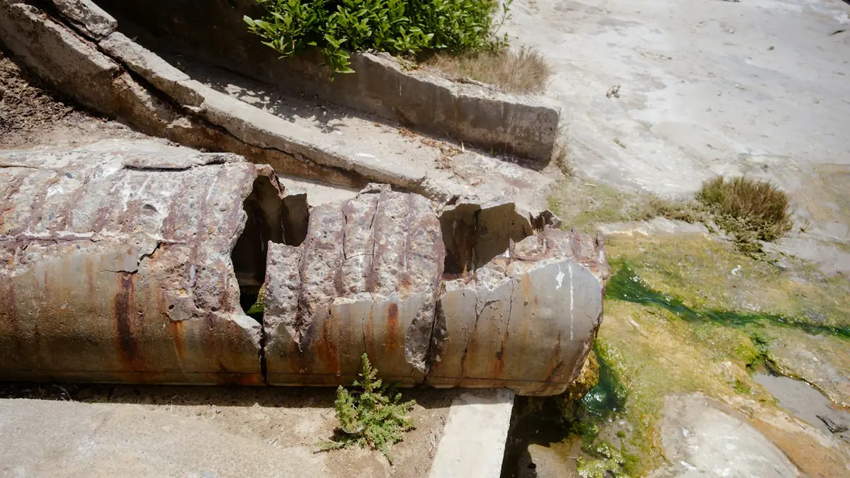 A rusted pipe broken open in the middle and lying in grass - Leak Detection in Folly Castle