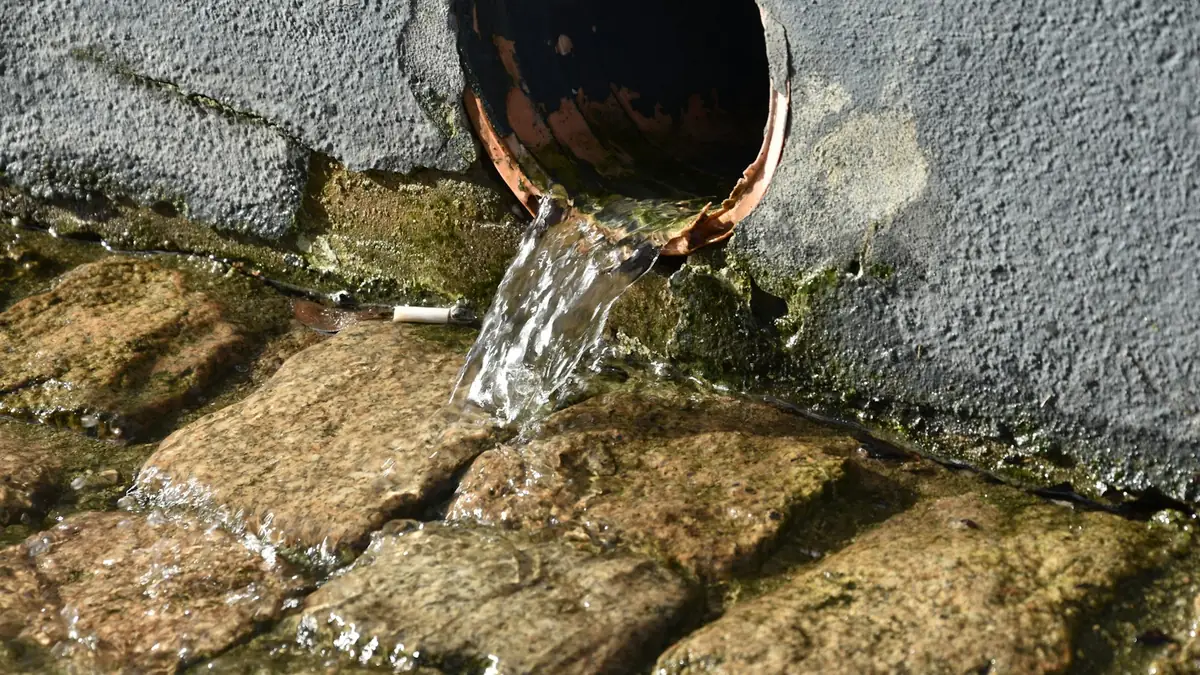 Water flowing from a round pipe onto old stone setts - Leak Detection in Folly Castle